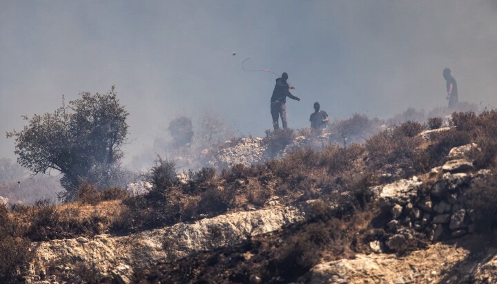 Masked Israeli settlers hurl rocks at Palestinians in the village of Sinjil on July 4. Photo: John Wessels/AFP via Getty