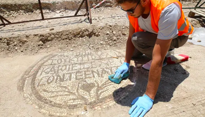 An archaeologist cleans the mosaic inscription at the entrance of a 5th-century Christian church. Photo: FOX News